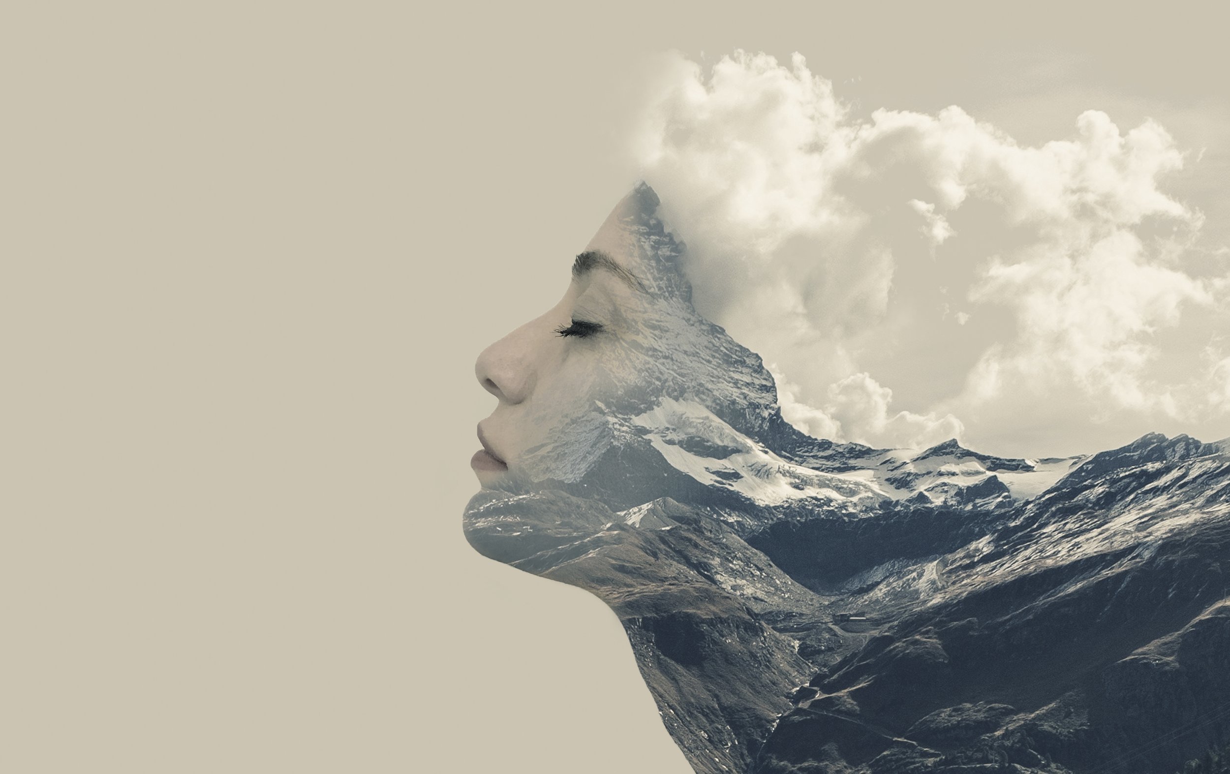 A woman’s profile with mountain and sky landscape integrated into her head, creating a double exposure effect.