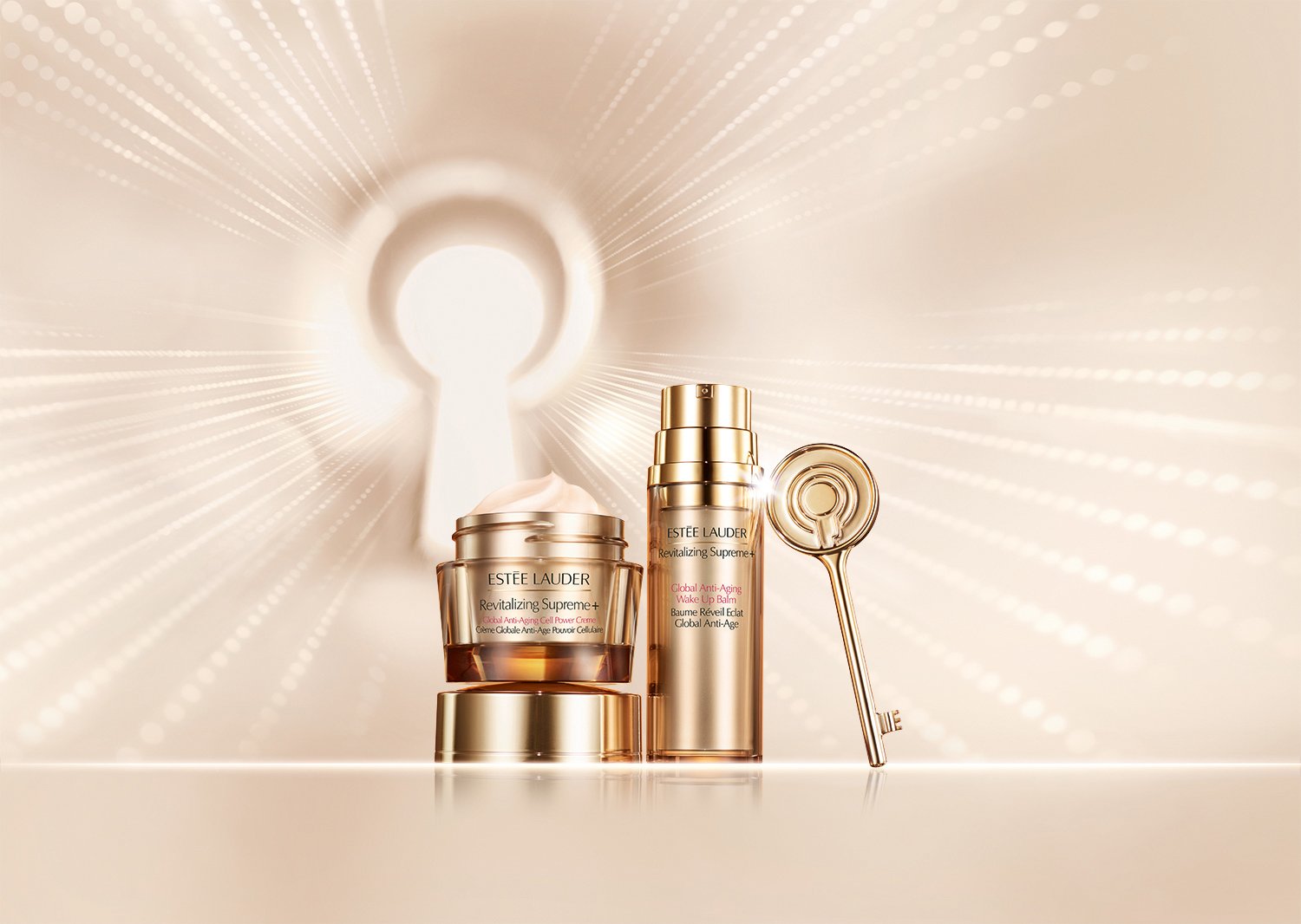Estée Lauder Revitalizing Supreme+ skincare products, including a jar of cream, a pump bottle, and a gold-colored facial roller, with a keyhole-shaped light source in the background.